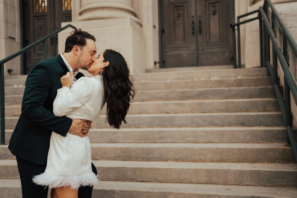 couple kissing on courthouse stairs in a downtown Dallas engagement session